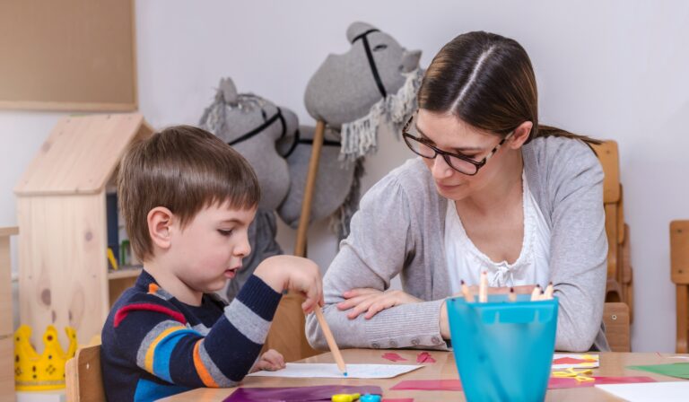 teacher sitting at a table working with a student
