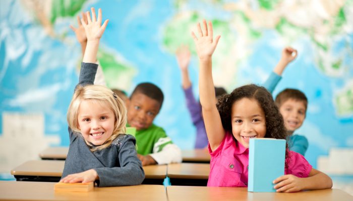 children raising their hands in class