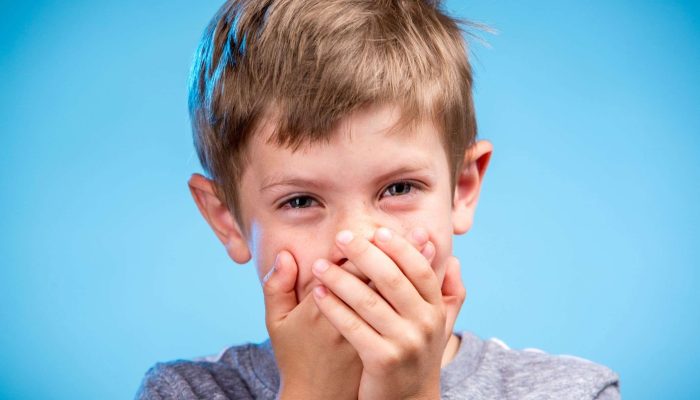 young boy laughing with hands over his mouth