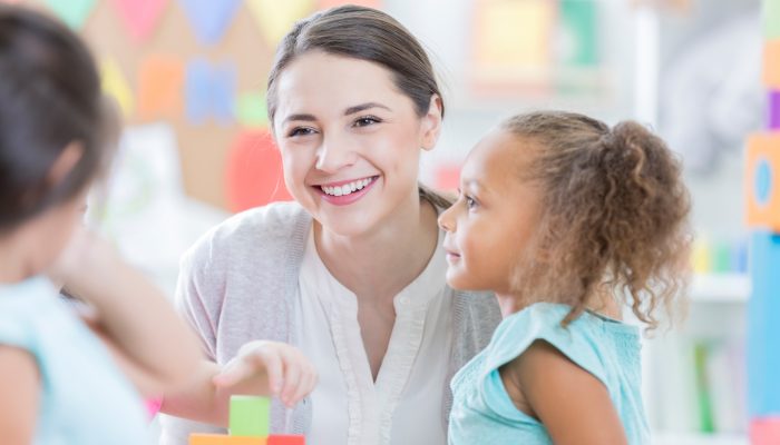 child sitting close to her teacher - attention seeking