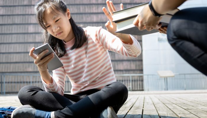 girl on her cell phone, pushing away textbooks