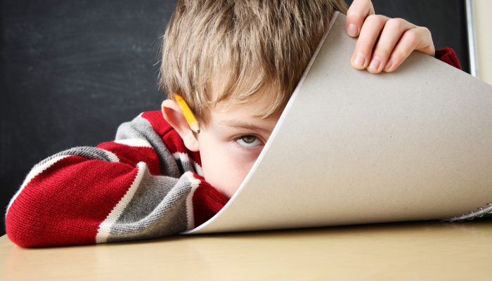 student hiding behind a notebook