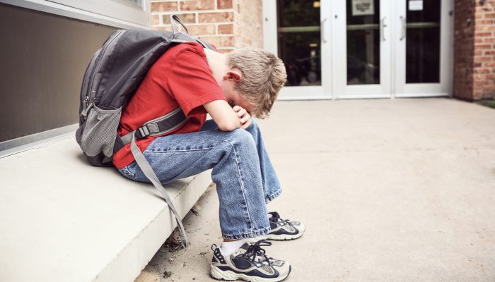 child sitting on bench with head on his arms