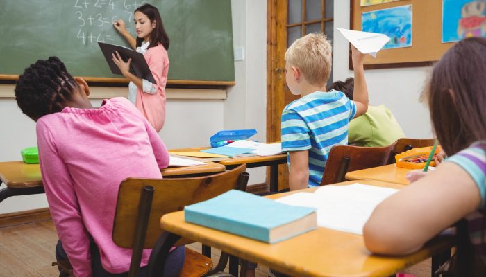 student preparing to throw a paper airplane in class