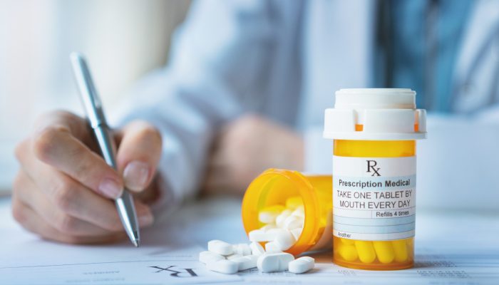 doctor writing a prescription with a bottle of medicine in front of him