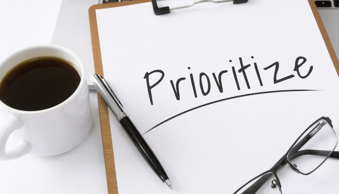 The word prioritize written on a paper on a clipboard