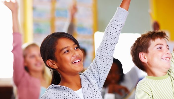 students raising their hands in class