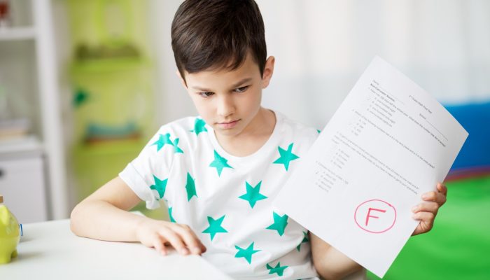 student holding a paper with a large red F on it