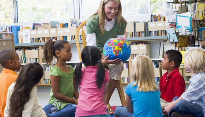 teacher students looking at globe