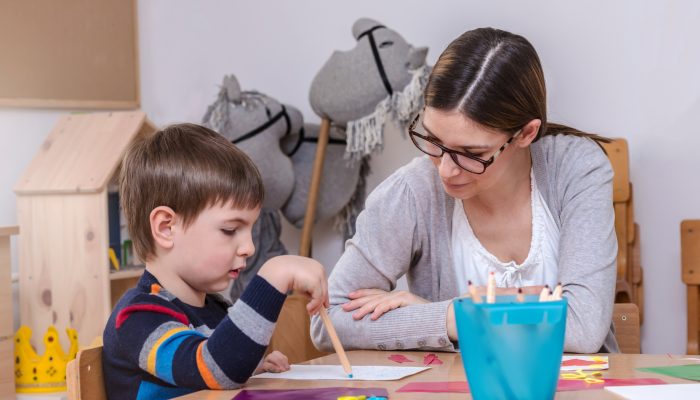 teacher sitting at a table working with a student